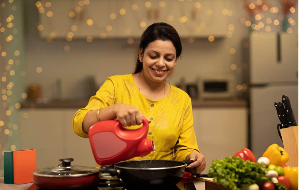 An Indian woman pouring oil in the kitchen to fry Goeld Frozen snacks, preparing a delicious treat with ease